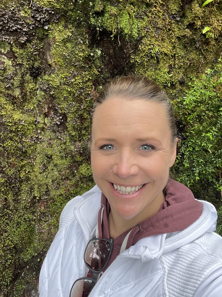 Photograph of Rebecca Higgins. Rebecca is wearing a white jacket, and her hair is pulled back in a ponytail.