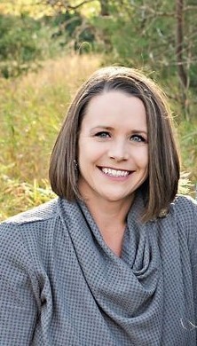 Photograph of Rebecca Higgins. Rebecca is wearing a gray blouse and is outside.